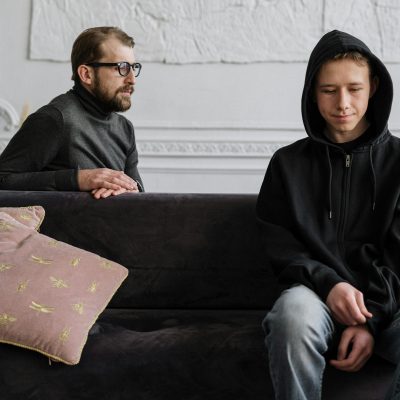 Teen in black hoodie during a therapy session in a calm indoor setting.