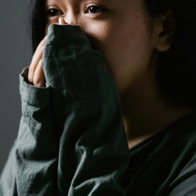 Close-up of a distressed woman indoors, showing anxiety and stress.