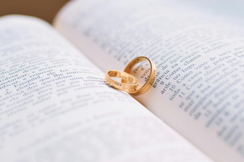 A pair of gold wedding rings resting on an open book, symbolizing love, commitment, and the journey of marriage therapy.